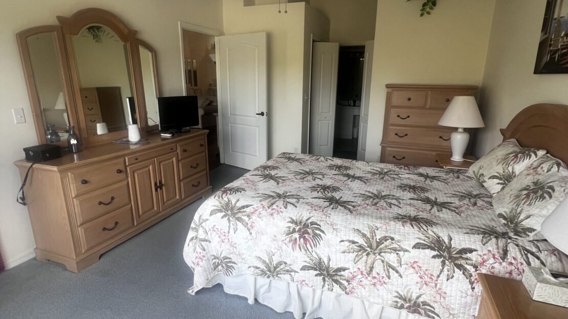 Cozy bedroom with tropical-themed bedding and wooden furniture.