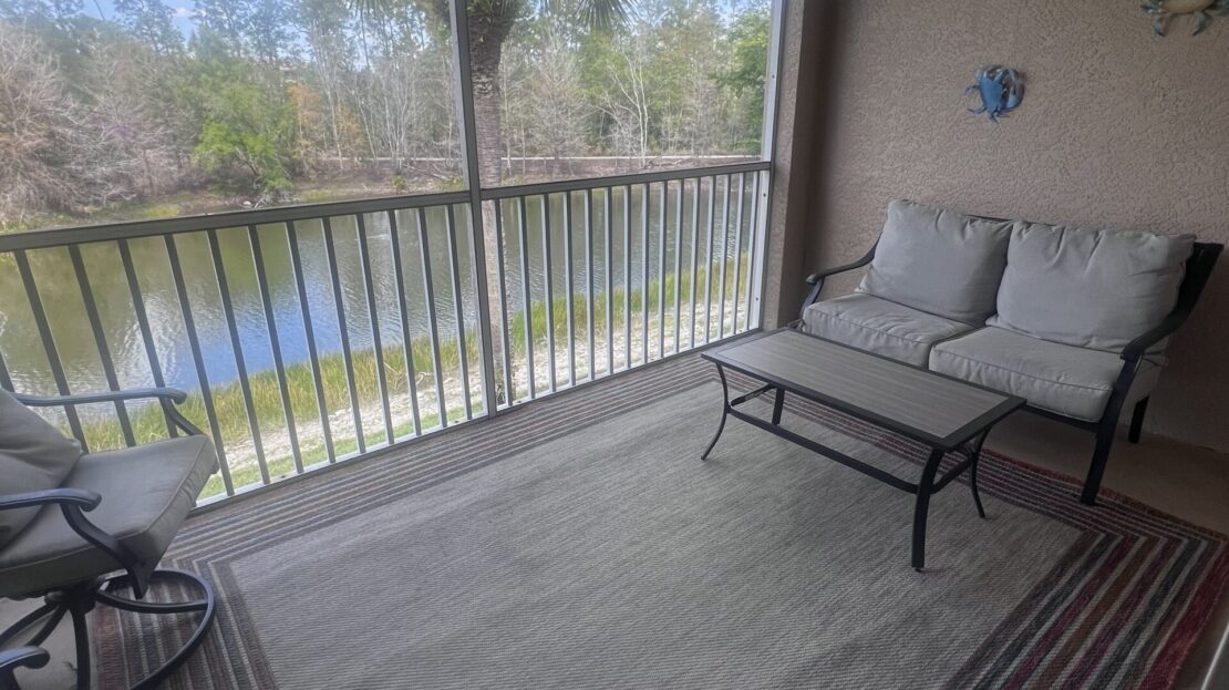 Cozy balcony with cushioned seating overlooking a serene lake.