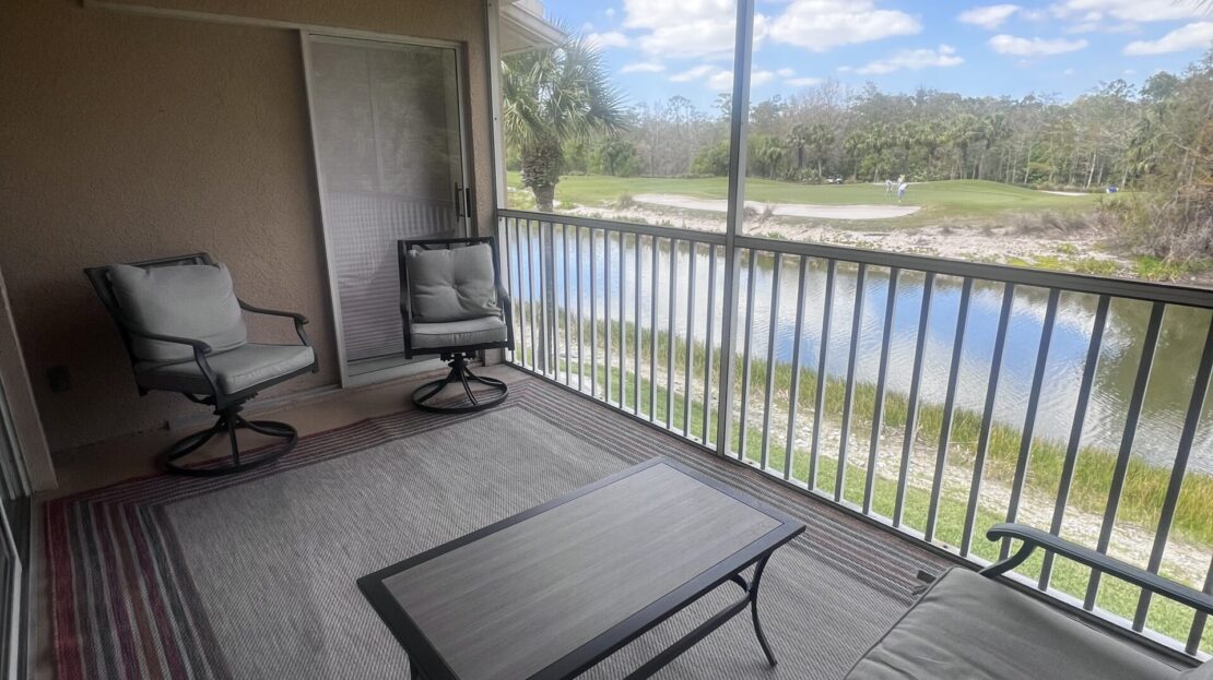 Balcony overlooking a serene waterway with comfortable seating and ceiling fan.