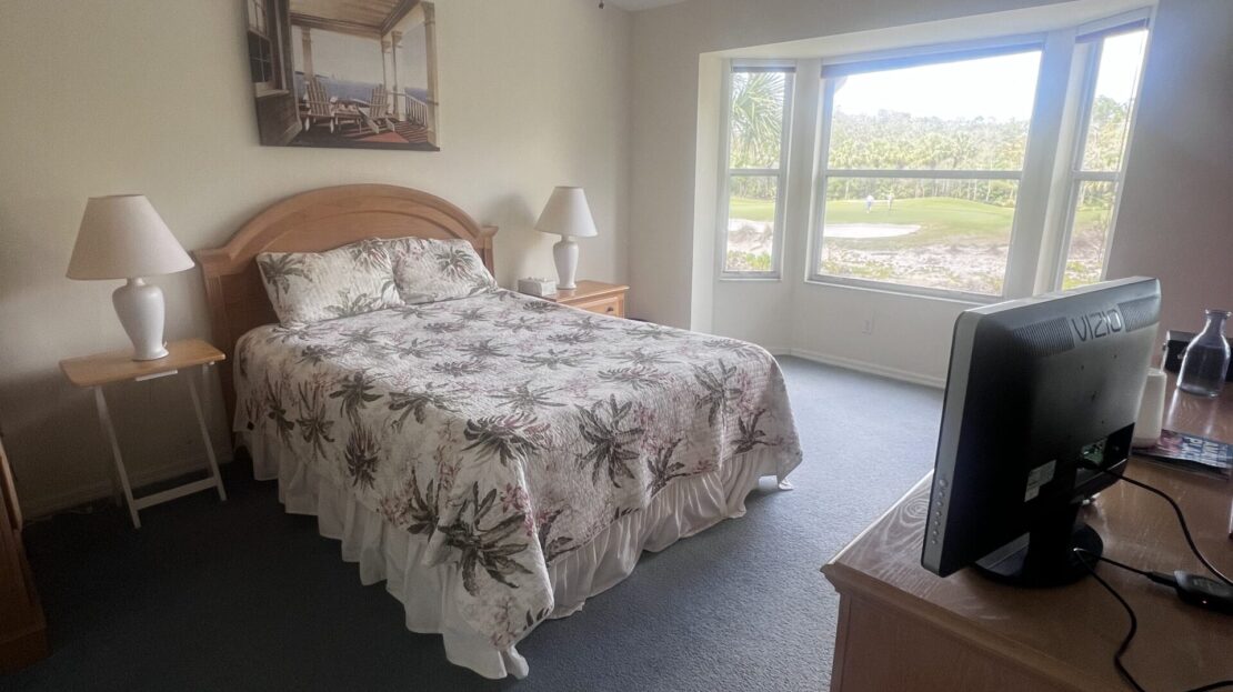 Cozy bedroom with floral bedding and large window view.