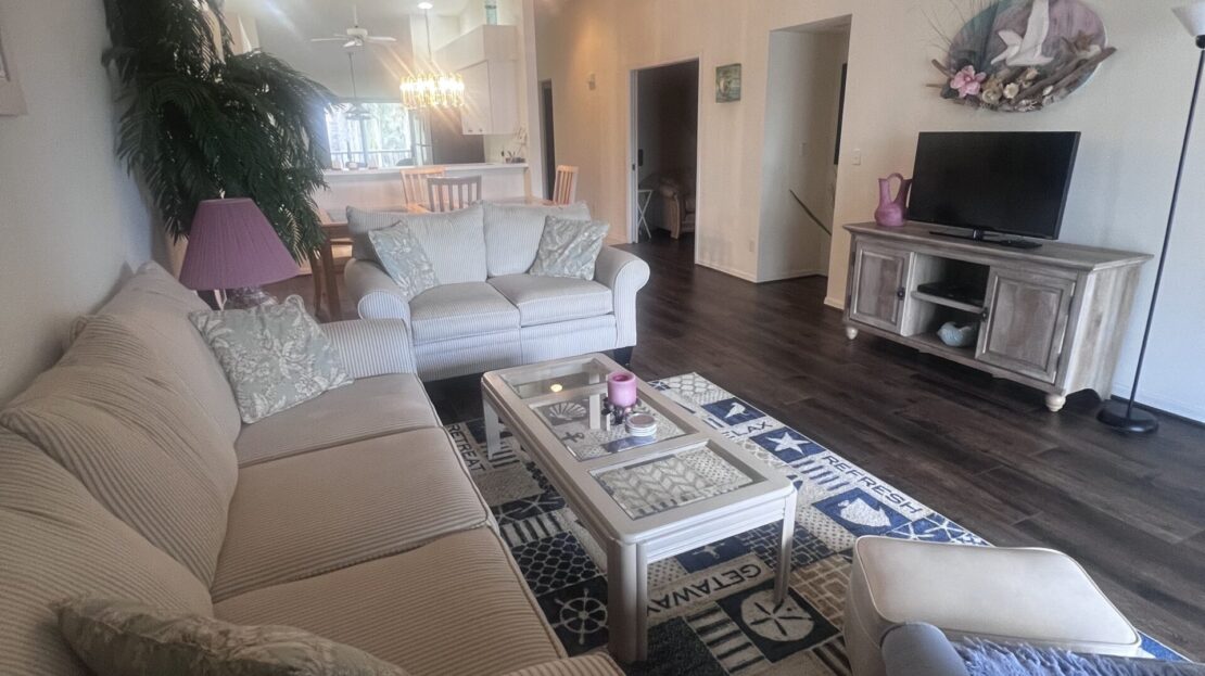 Cozy living room with beige sofas, a fireplace, and plants.