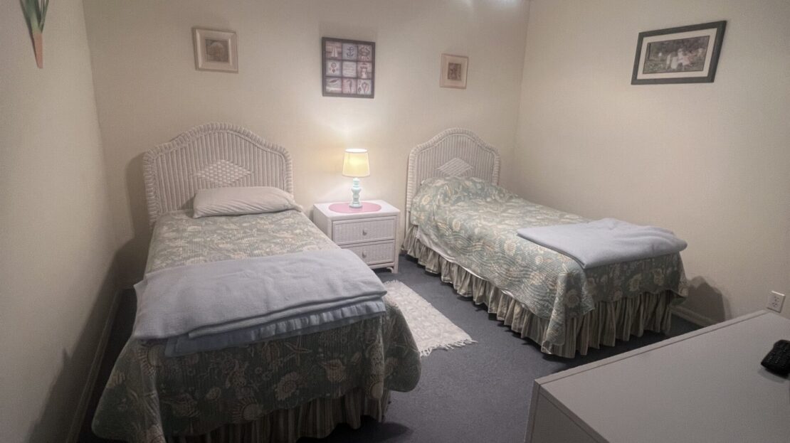 Cozy bedroom with two twin beds, a ceiling fan, and soft lighting.