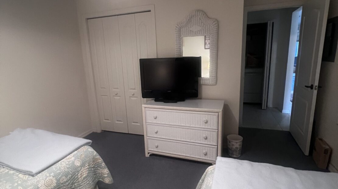 Cozy bedroom with two beds, a dresser, and a TV.
