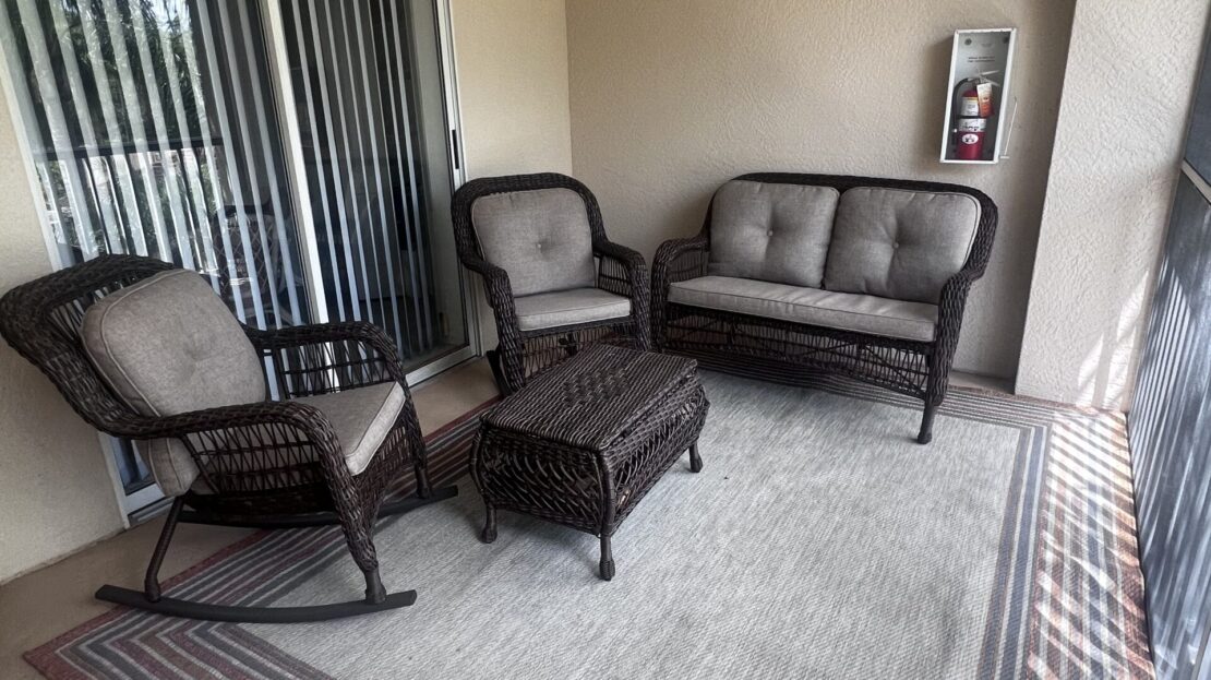 Cozy outdoor seating area with rocking chairs and a loveseat on a rug.