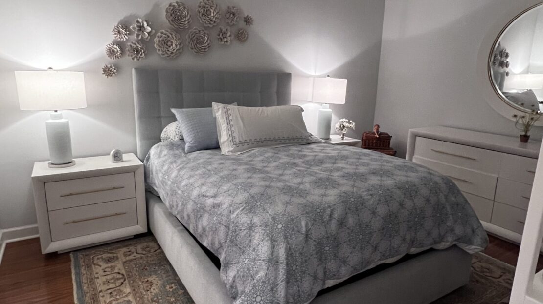 Cozy bedroom with a gray bed, nightstands, and soft lighting.