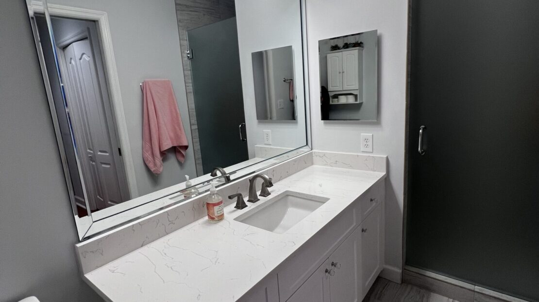 Modern bathroom with a large mirror and countertop sink.