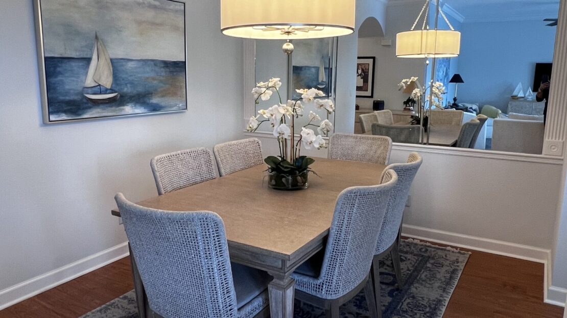 Elegant dining room with a wooden table, cushioned chairs, and a large mirror.