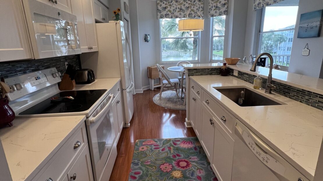 Bright modern kitchen with white cabinets and colorful floral rug.