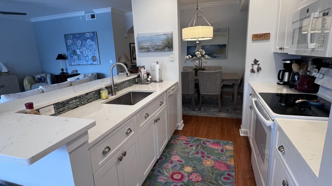 Bright modern kitchen with white cabinetry and a colorful rug.