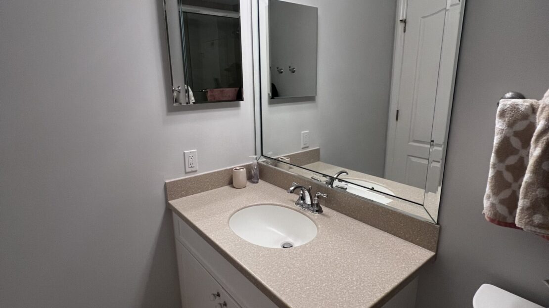 Modern bathroom with white vanity, mirror, and soft lighting.