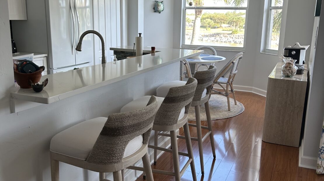Modern kitchen with island seating and a child peeking over the counter.
