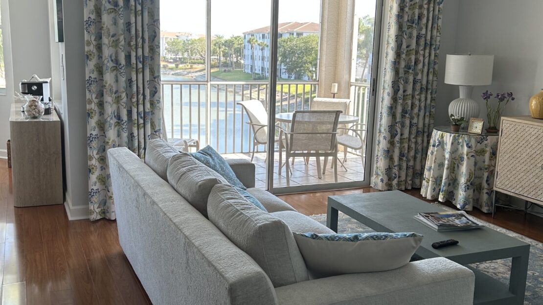 Bright living room with gray sofa and glass doors opening to a balcony.