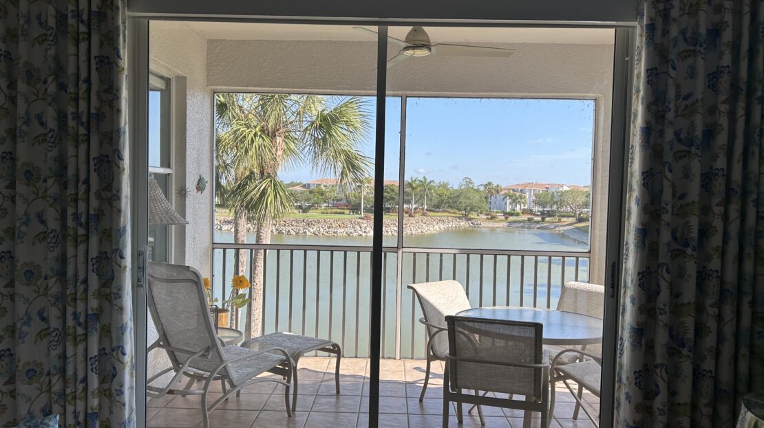 Balcony overlooking a serene waterfront with chairs and a table.