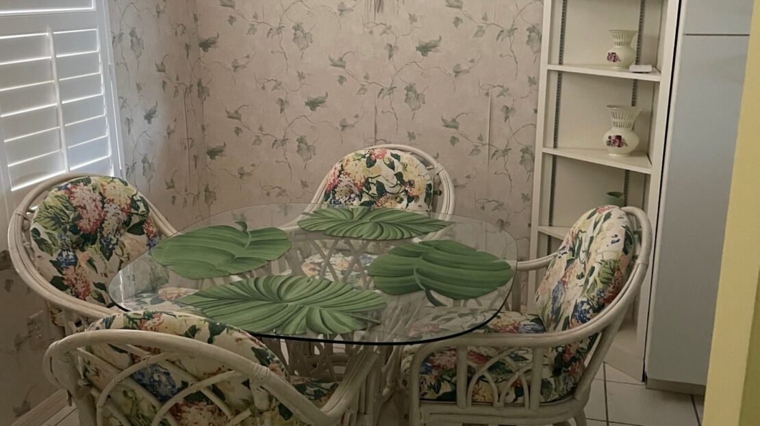 Cozy dining nook with floral wallpaper and rattan furniture.