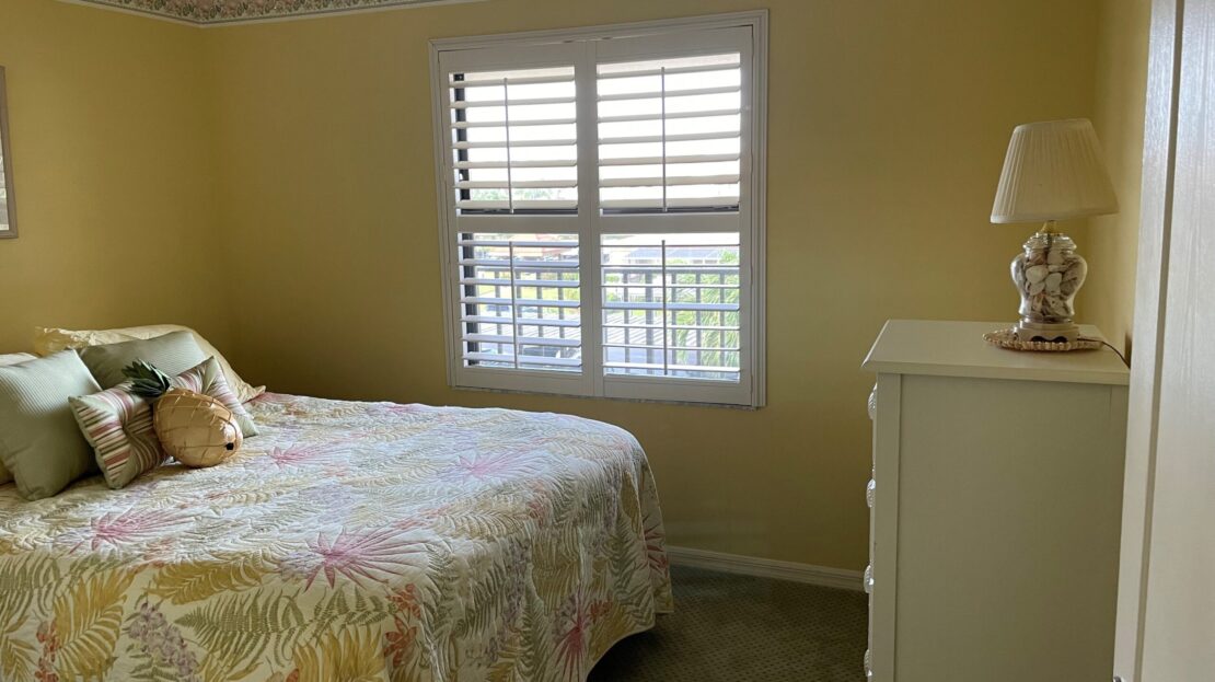 Cozy bedroom with floral bedding and a window letting in natural light.