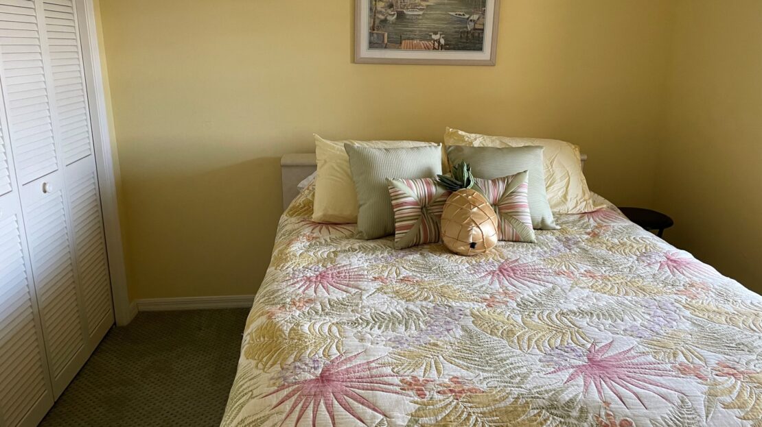 Cozy bed with floral bedding and decorative pillows in a warmly lit bedroom.