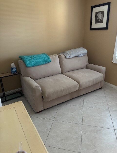 Beige sofa with folded blankets and side table in a cozy corner.
