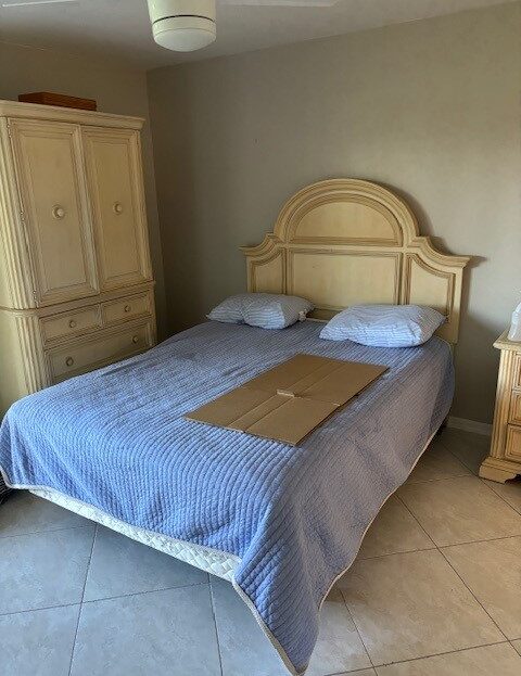 Bedroom with beige furniture and a blue bedspread.