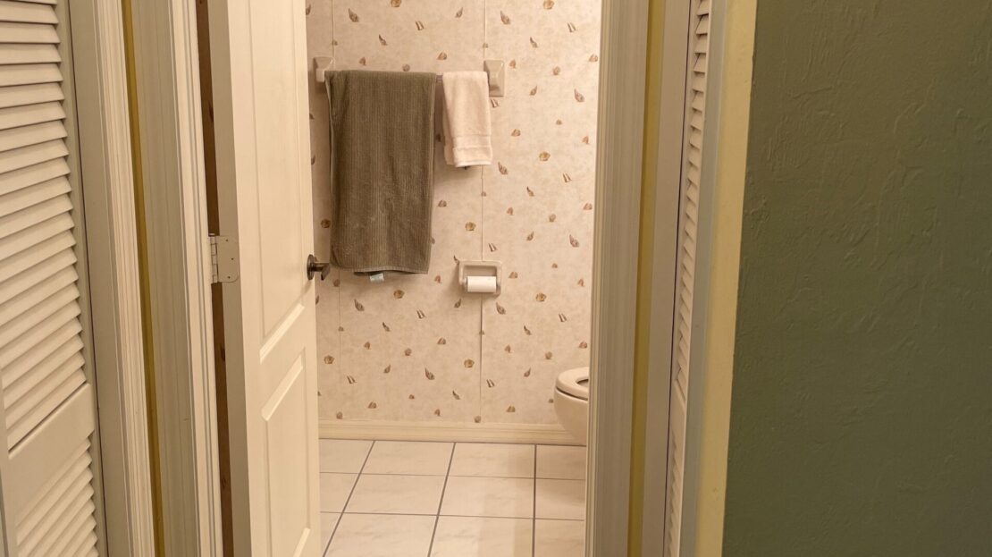 A hallway leading to a bathroom with a towel on the wall.