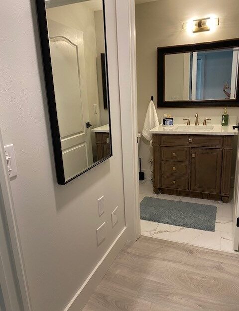 Modern bathroom with wooden vanity and large mirror.