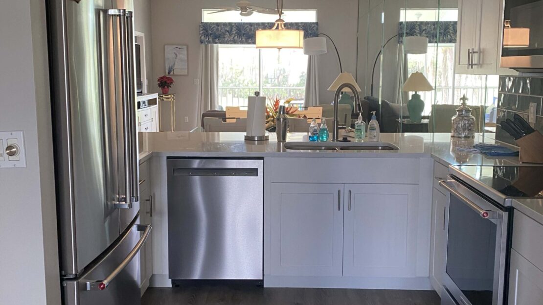Modern kitchen with stainless steel appliances and white cabinetry under warm lighting.