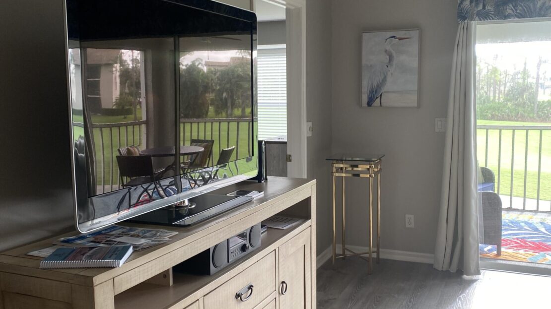 Modern living room with a large TV and wooden console near a sliding glass door.