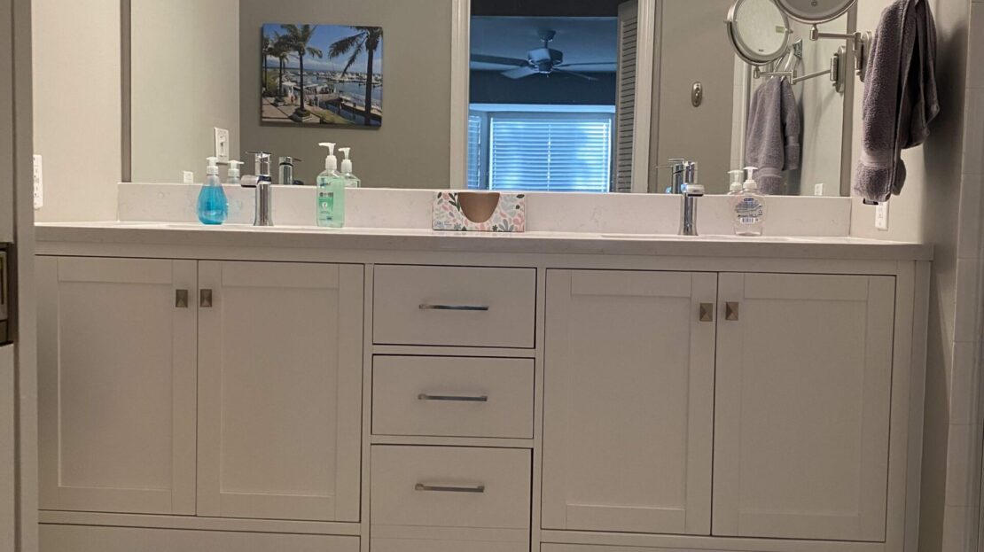 Modern white bathroom vanity with a large mirror and various toiletries.
