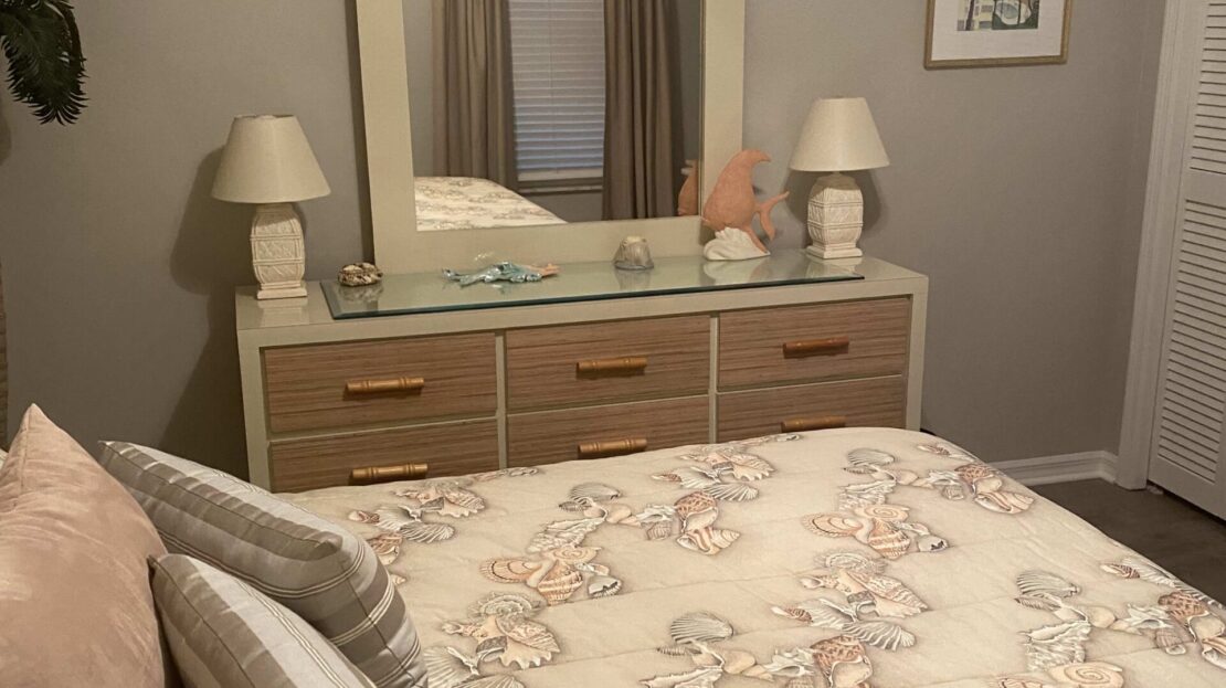 Cozy bedroom with floral bedding and a wooden dresser with lamps.