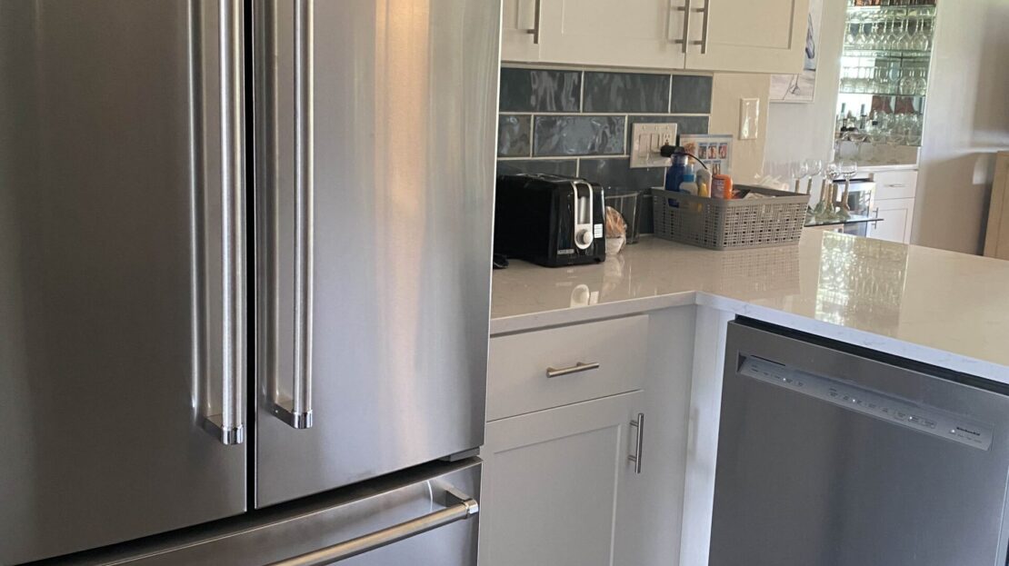 Modern kitchen area with stainless steel appliances and white cabinetry.