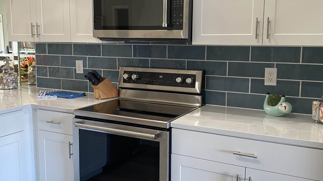 Modern kitchen with stainless steel appliances and blue subway tile backsplash.