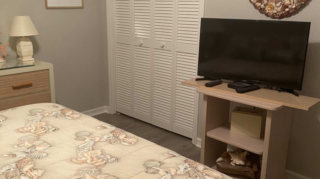 Cozy bedroom with a floral bedspread and a small TV on a wooden stand.