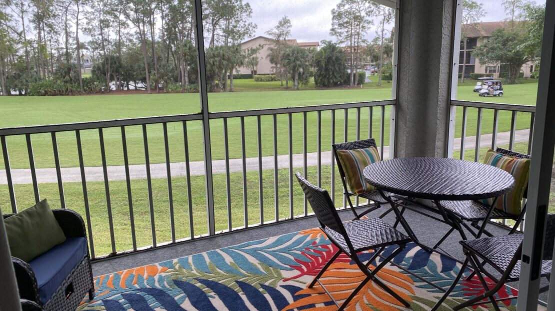 Covered patio overlooking a grassy golf course with outdoor furniture.