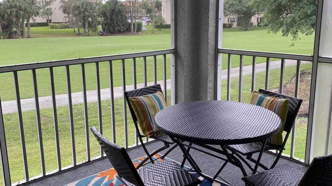 Cozy patio with a round table and four chairs overlooking a green lawn.