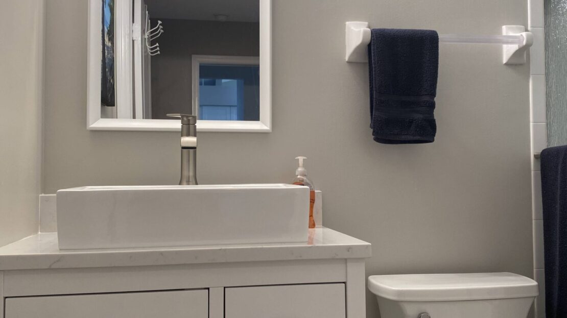 Minimalist bathroom with white vanity, mirror, and toilet.