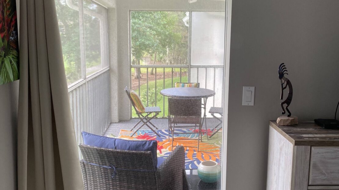 Cozy outdoor seating area with wicker chairs and a table on a porch.