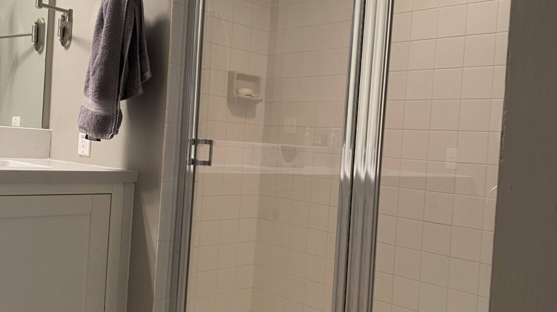A modern bathroom with a glass shower and vanity area.