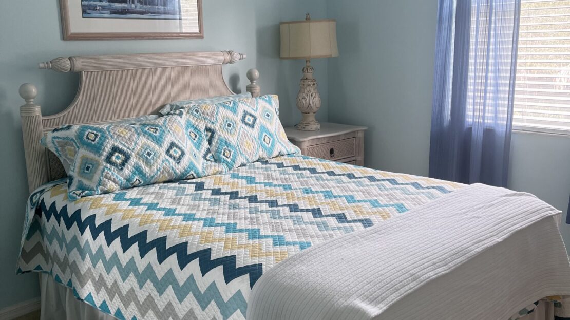 Cozy bedroom with a patterned bedspread and soft lighting.