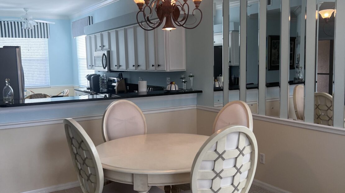 Elegant dining area with round table and classic chairs under chandelier.