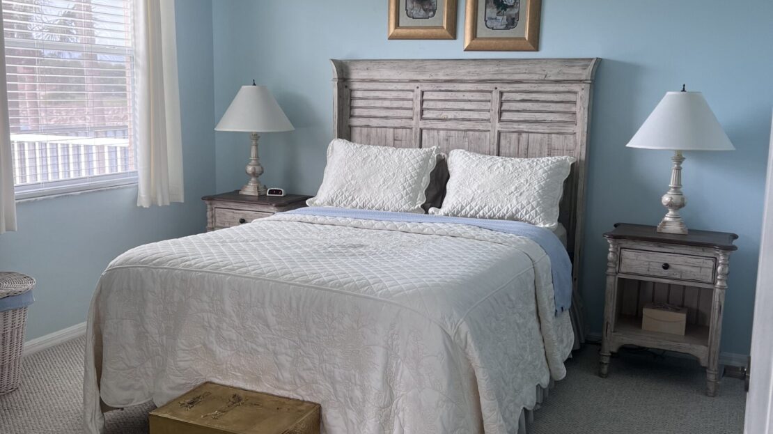 Cozy bedroom with a white bedspread and light blue walls.