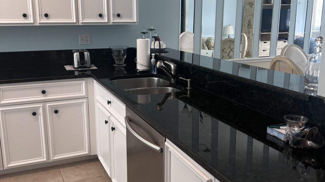 Modern kitchen with white cabinets and black countertops.