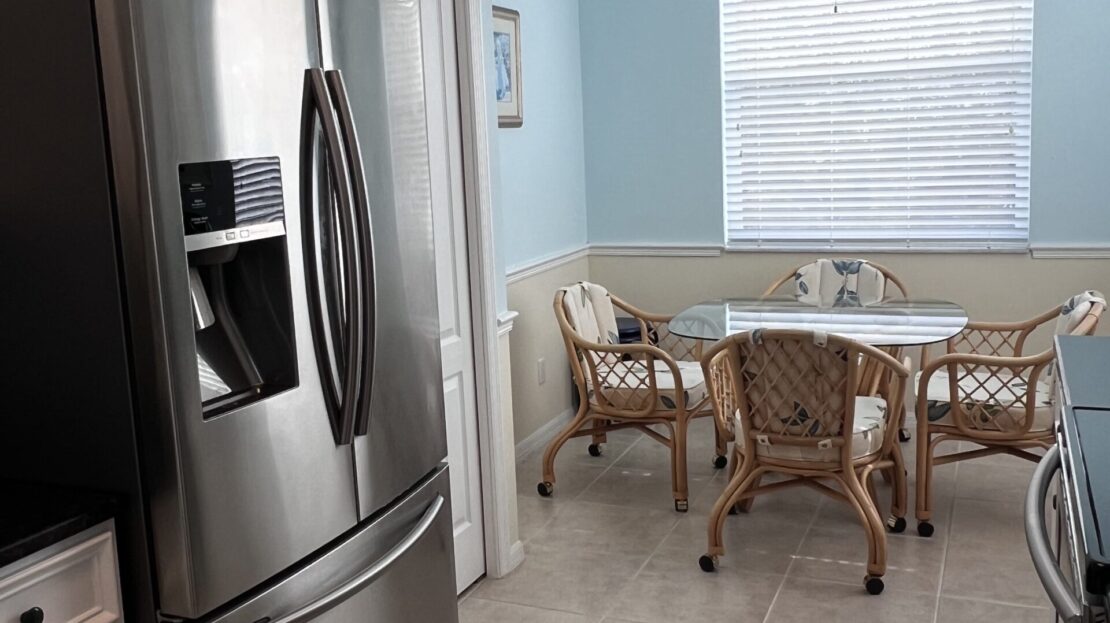 Modern kitchen with stainless steel fridge and cozy dining area.