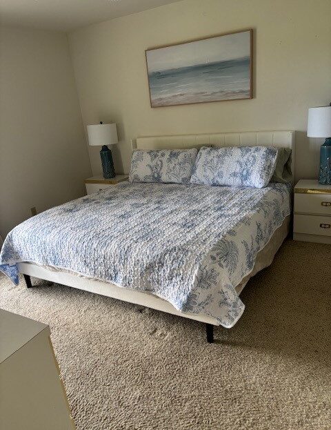 Neatly made bed with patterned bedding and two bedside lamps in a cozy bedroom.