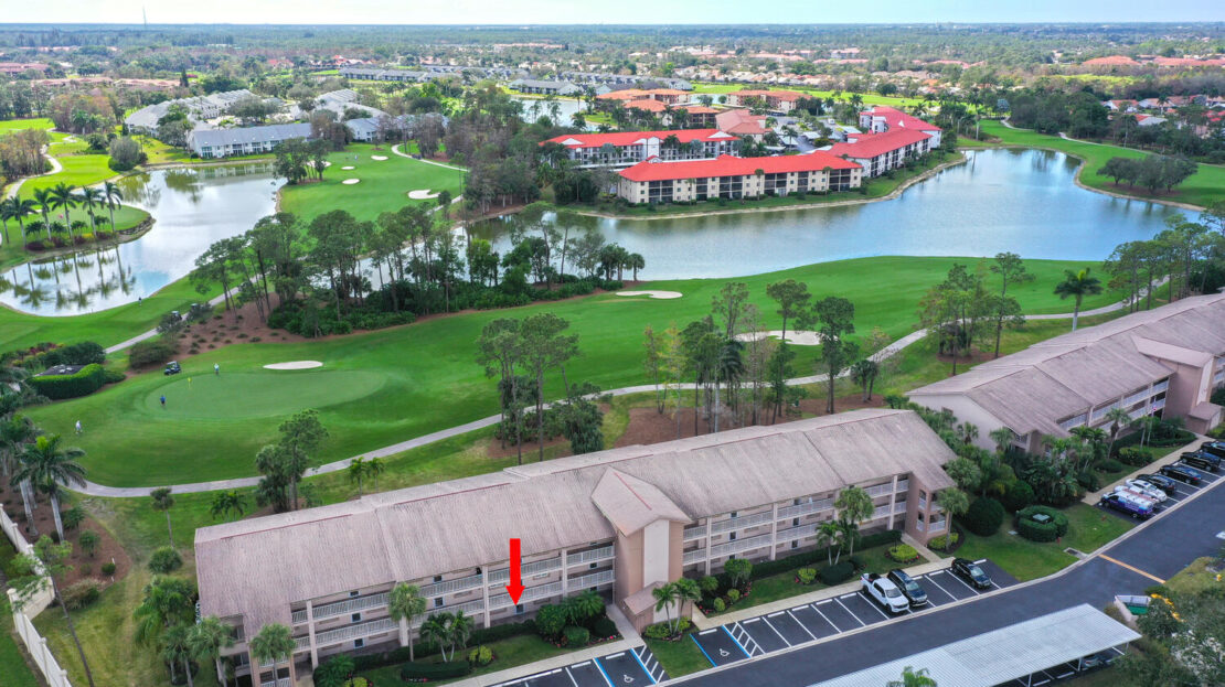 Aerial view of a residential area beside a golf course and water body.
