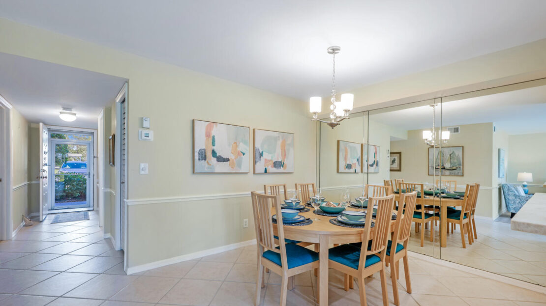 Bright dining area with wooden table and chairs, modern chandelier, and abstract wall art.