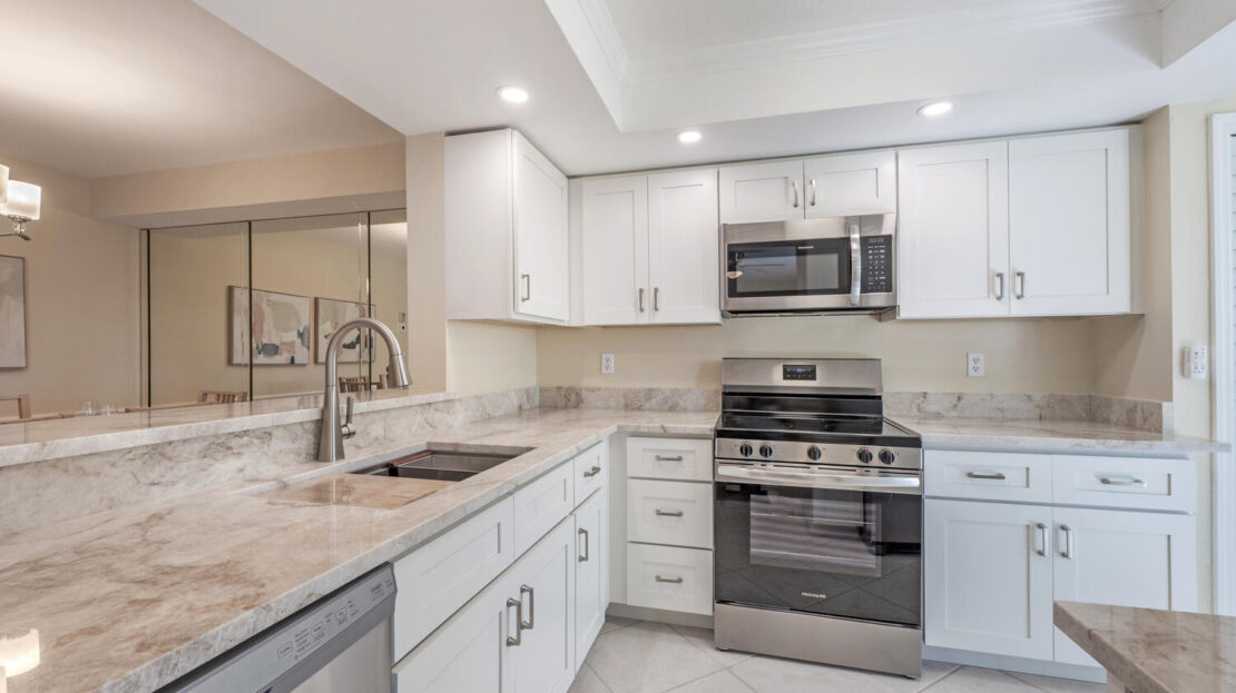 Modern white kitchen with stainless steel appliances and granite countertops.