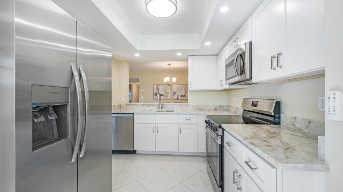 Modern kitchen with white cabinets and stainless steel appliances.