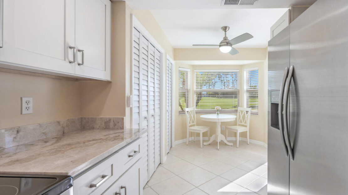 Bright modern kitchen with white cabinetry and a cozy dining nook by the window.