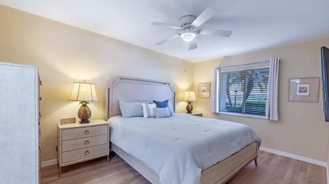 Cozy, well-lit bedroom with light decor and large window.