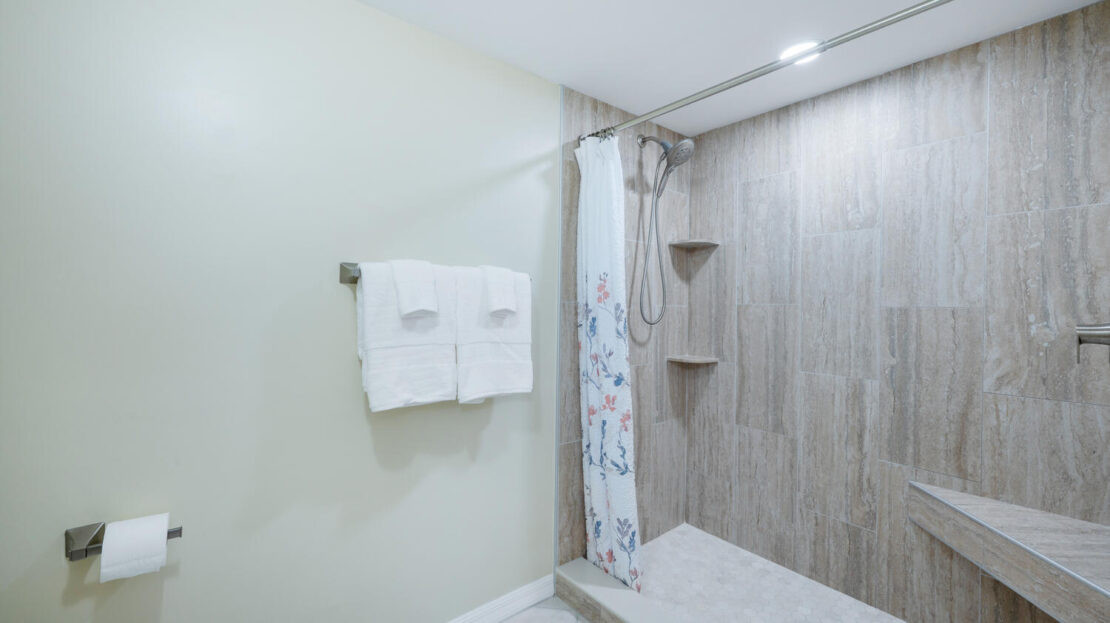 Modern bathroom with a walk-in shower and white towels.