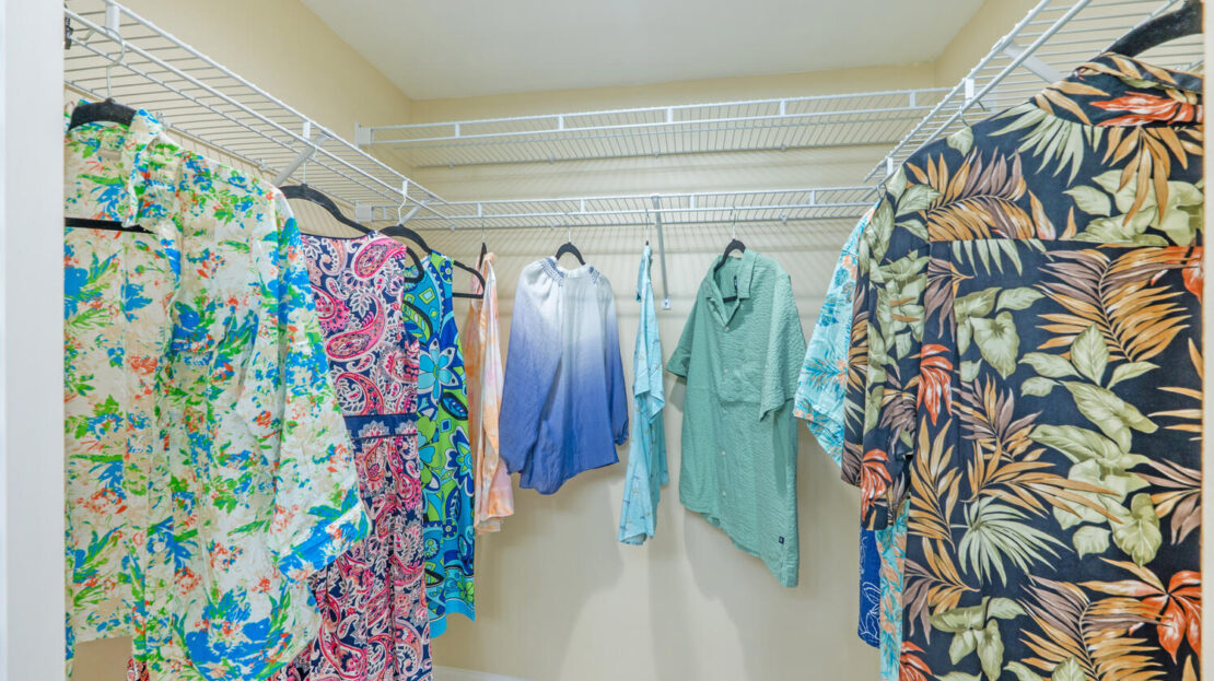 Colorful and patterned shirts hanging on a closet rod.